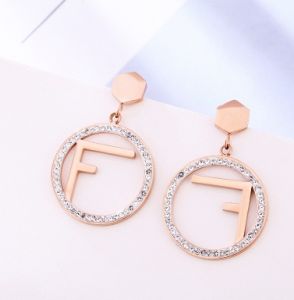 TT5557 - Bông tai titan FENDI mặt tròn viền đá (vàng hồng)