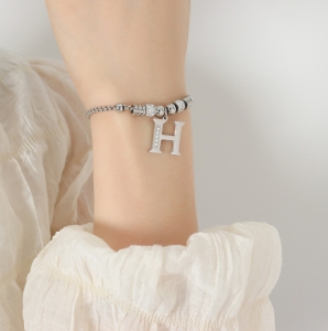 TTN8549 - Lắc tay titan dây rút phối charm H (màu trắng)